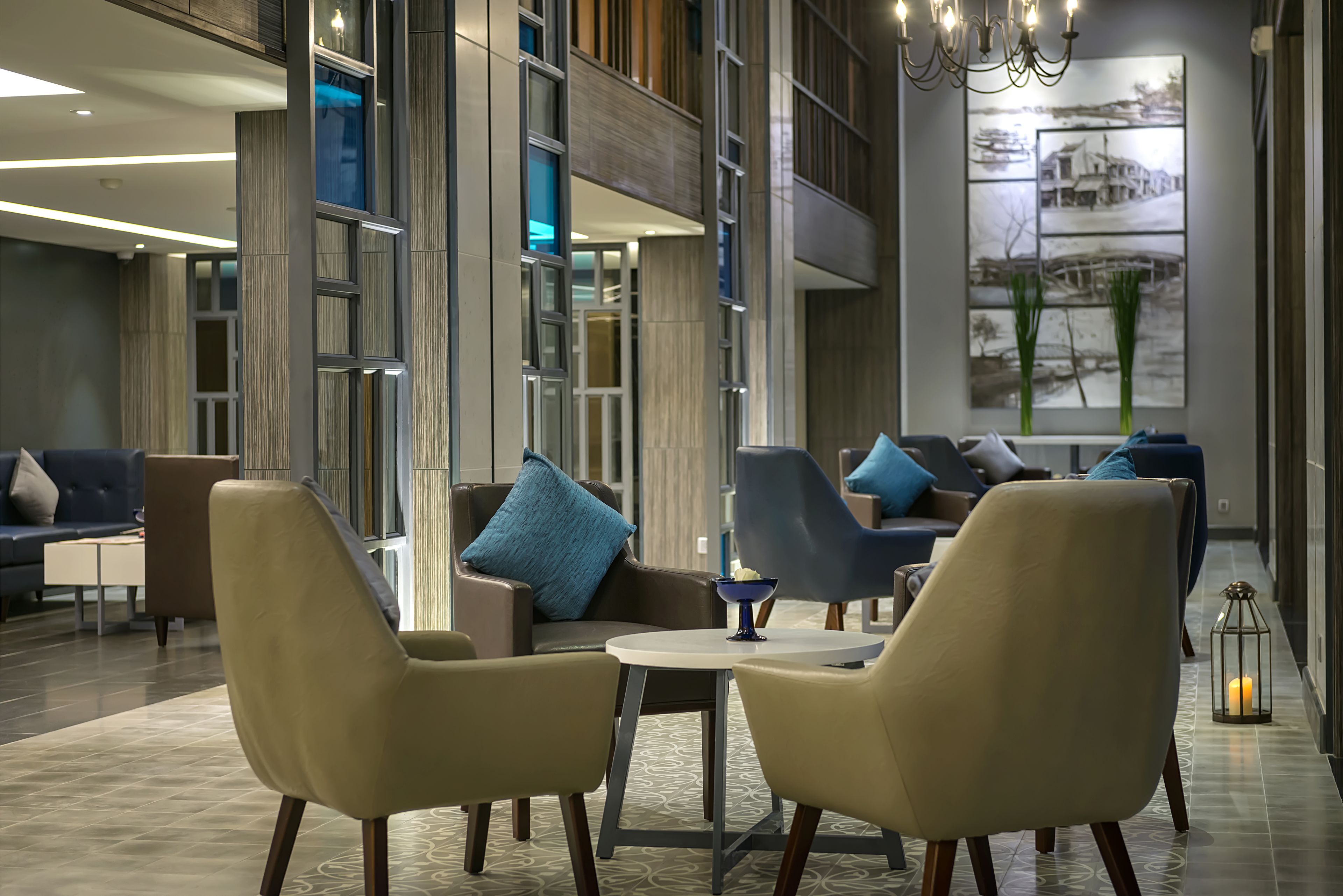 A modern lobby with a seating area, a chandelier, and a large wall art piece.