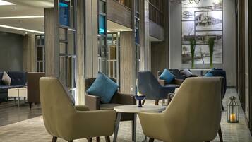 A modern lobby with a seating area, a chandelier, and a large wall art piece.
