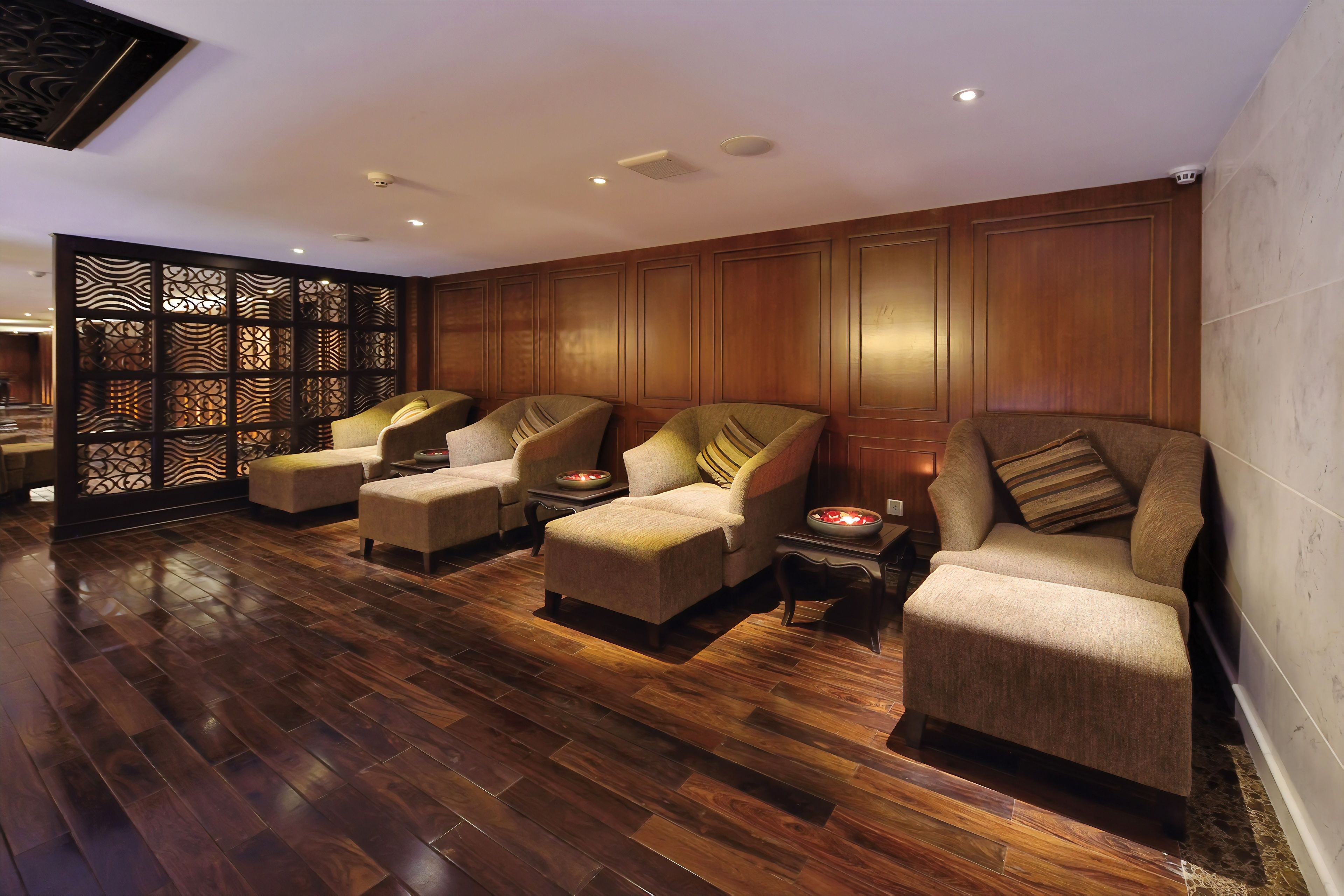 A spa area with four cushioned chairs, a wooden floor, and a decorative partition.