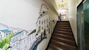 Un escalier avec des marches en bois et une fresque représentant des bâtiments sur le mur.