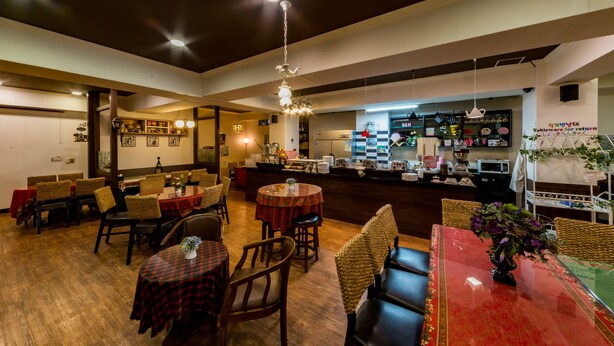 L'intérieur d'un restaurant, avec plusieurs tables, des chaises et un coin bar.