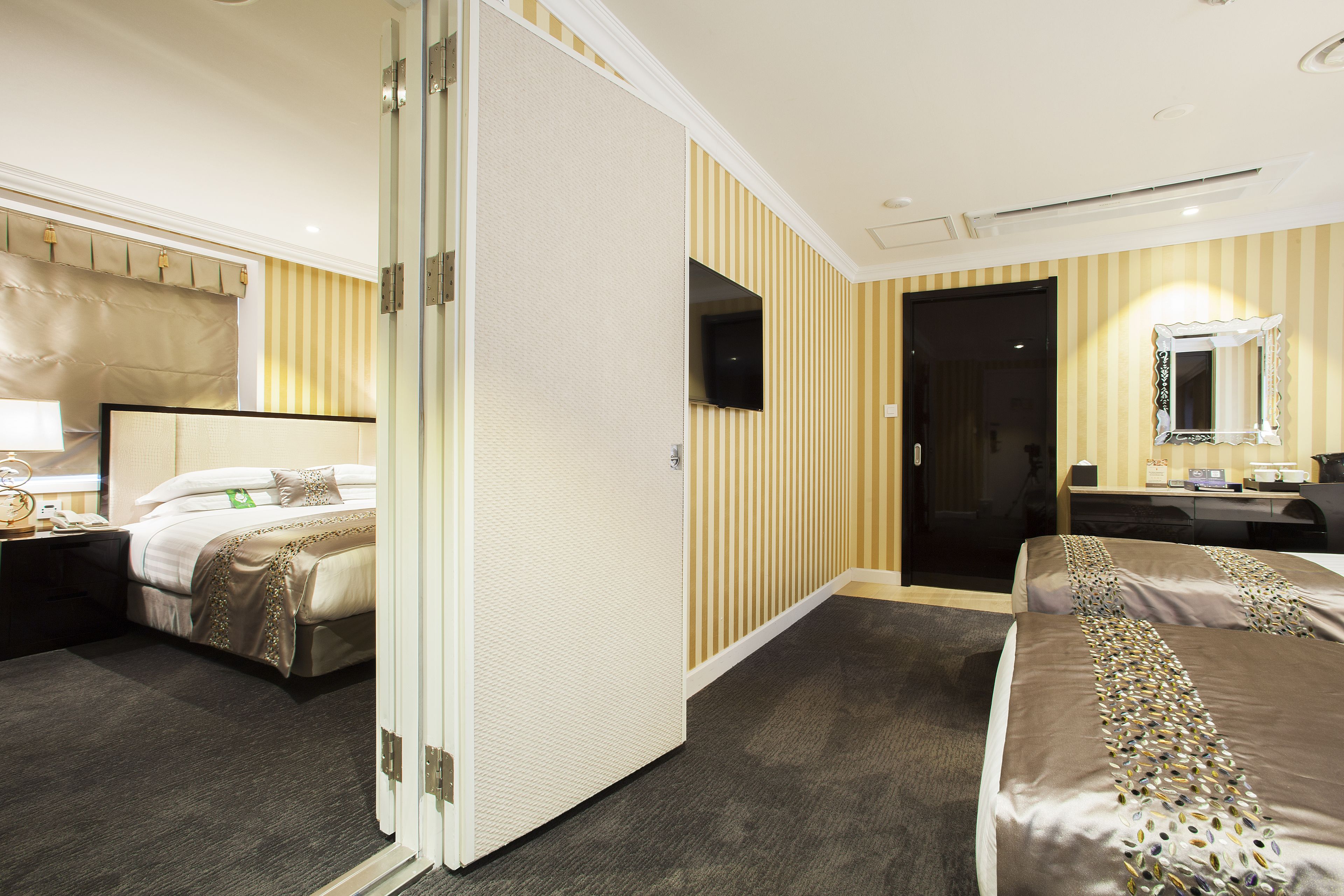 A hotel room with a bed, bedside table, lamp, and a mirror.