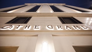 A building facade with illuminated letters spelling "THE GRAND".