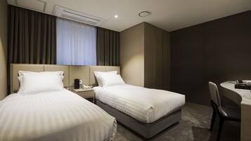 A hotel room with two beds, a desk, and a chair.