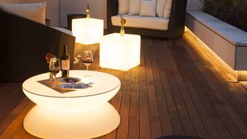 An outdoor seating area with a round table, two chairs, a sofa, and a small round stool.