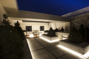 A modern outdoor patio area with a minimalist design, featuring a seating area and planters.