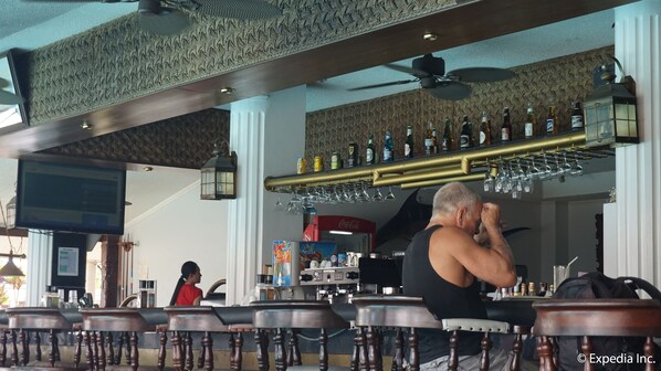 A bar area with a counter, stools, and a variety of bottles and glasses.