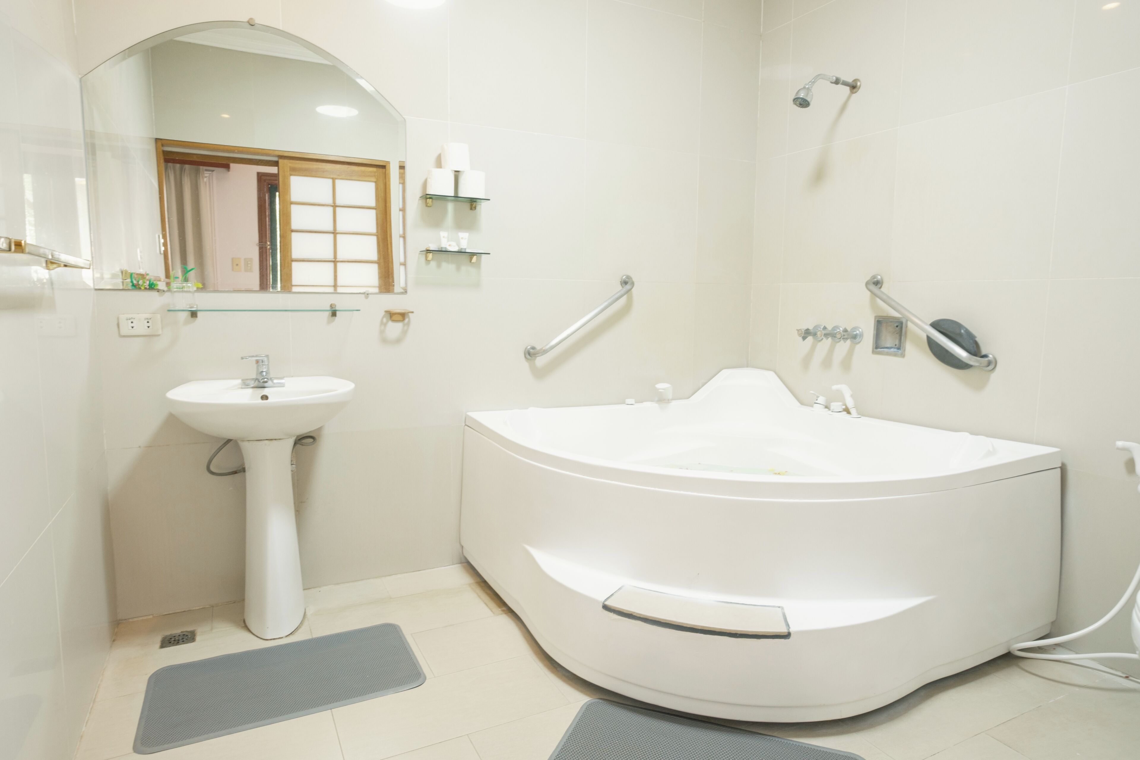 A modern bathroom with a freestanding bathtub, a pedestal sink, and a large mirror.