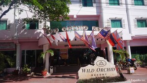 Exterior del Resort Wild Orchid, con varias banderas, un cartel y un letrero de bienvenida.