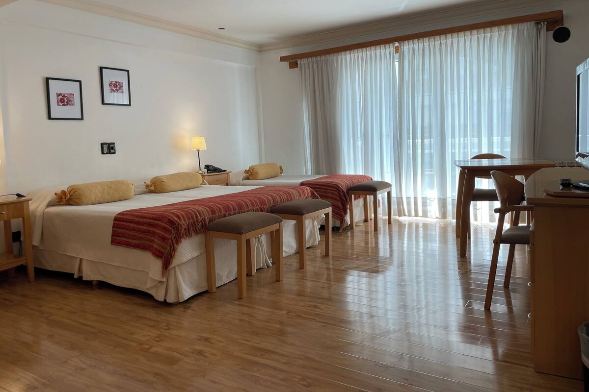 Ein Hotelzimmer mit zwei Betten, einem Schreibtisch und einem Stuhl.