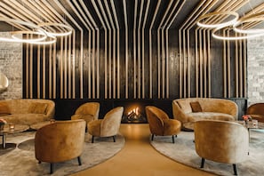 Ein moderner Lounge-Bereich mit Kamin, bequemen Sitzmöglichkeiten und einem außergewöhnlichen Deckenstil.