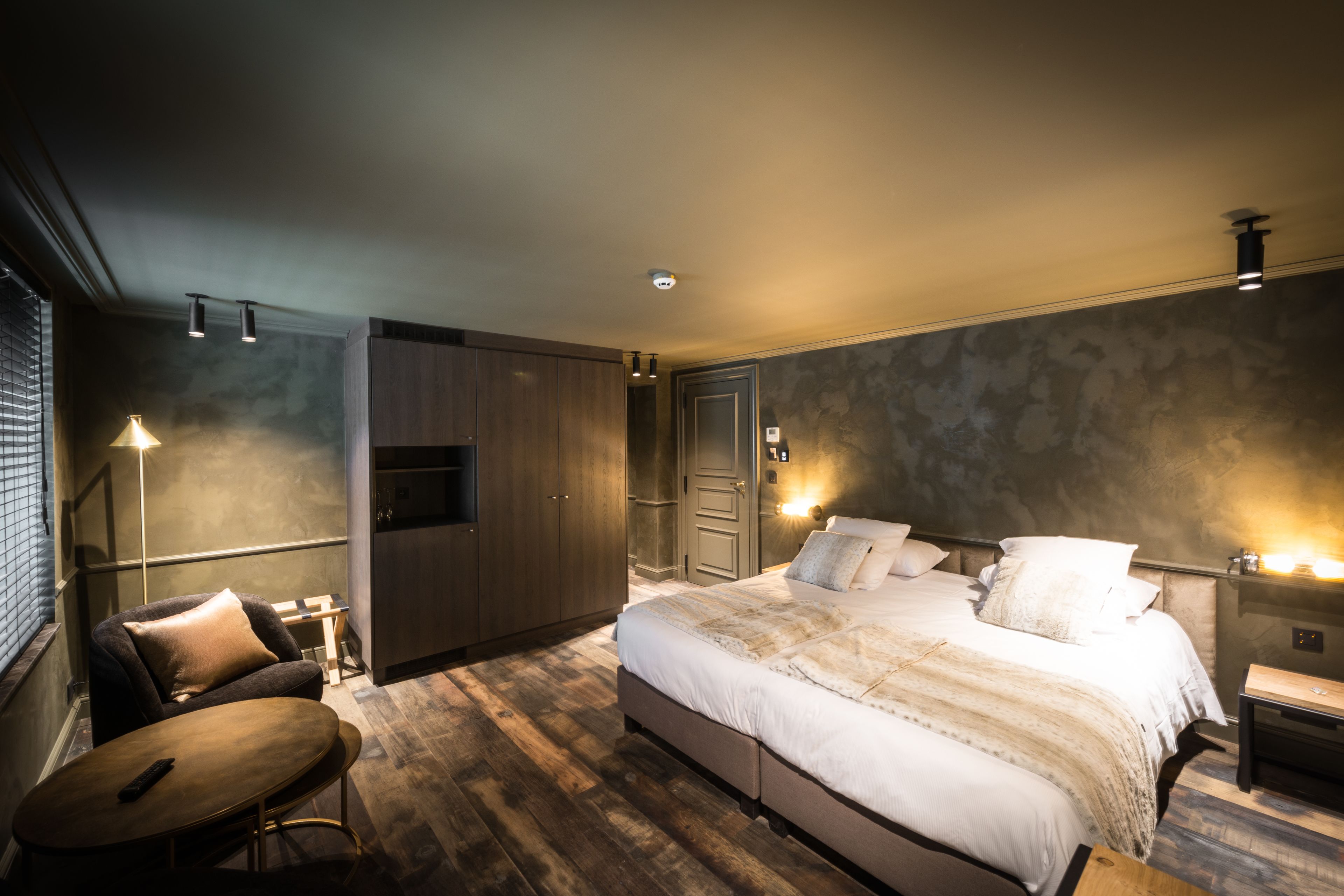 A modern bedroom with a large bed, a desk, and a chair.