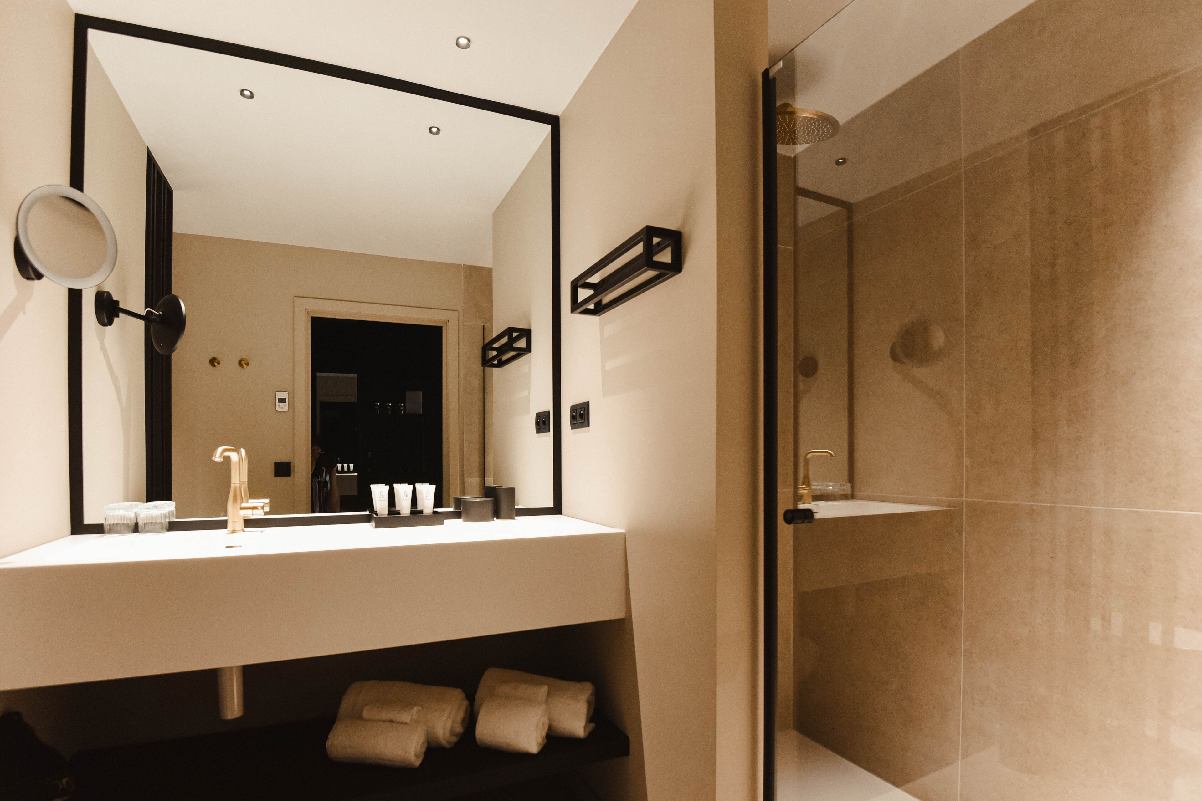 A modern bathroom with a large mirror, a sink, and a shower area.
