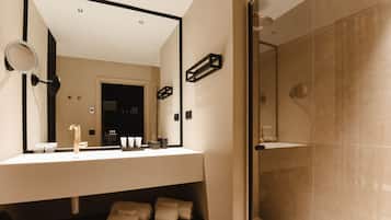 A modern bathroom with a large mirror, a sink, and a shower area.