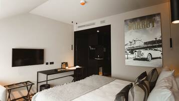 Una habitación de hotel moderna con una cama grande, un escritorio y un televisor de pantalla plana montado en la pared.