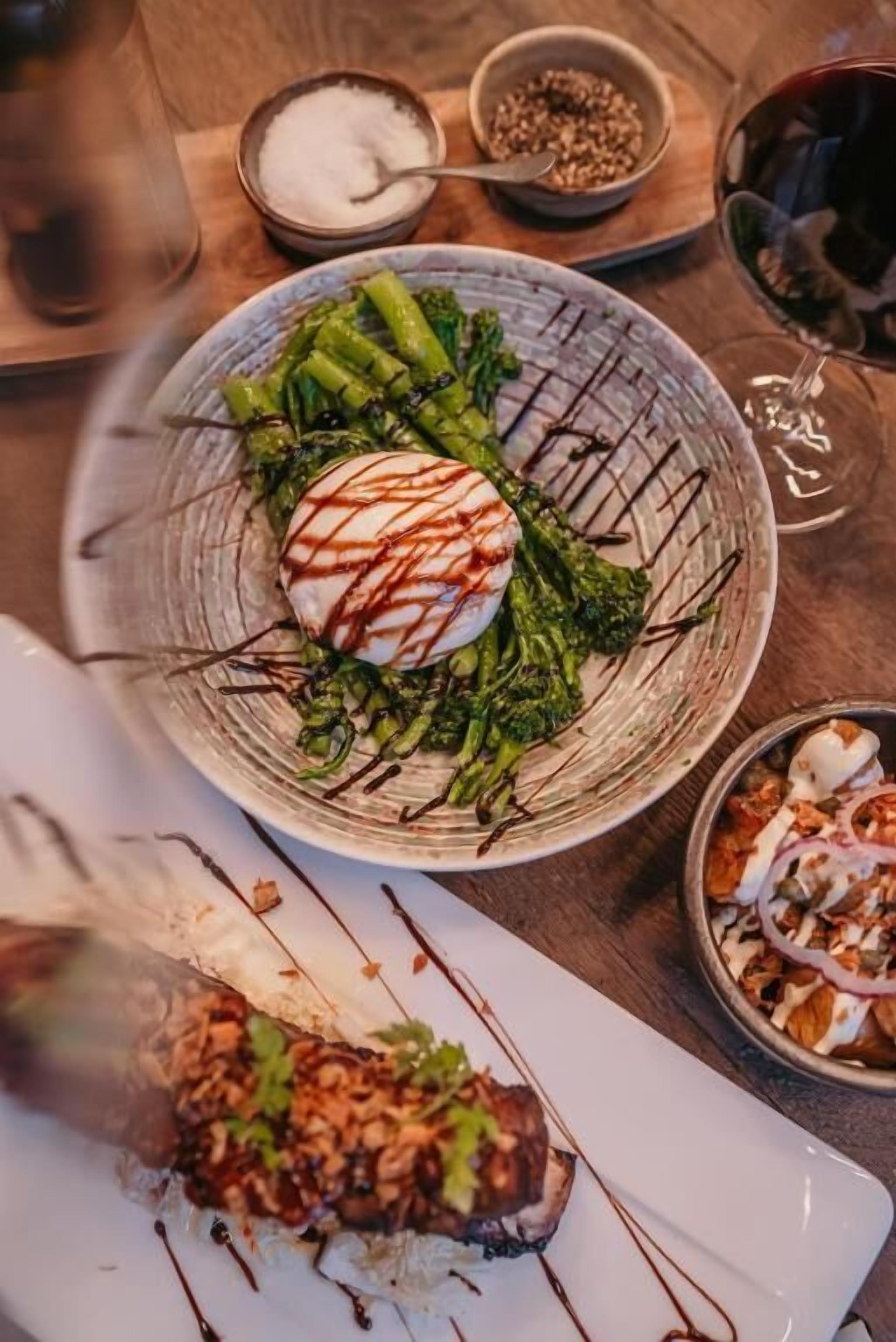 A dining table with a plate of food, a glass of red wine, and a bowl of nuts.