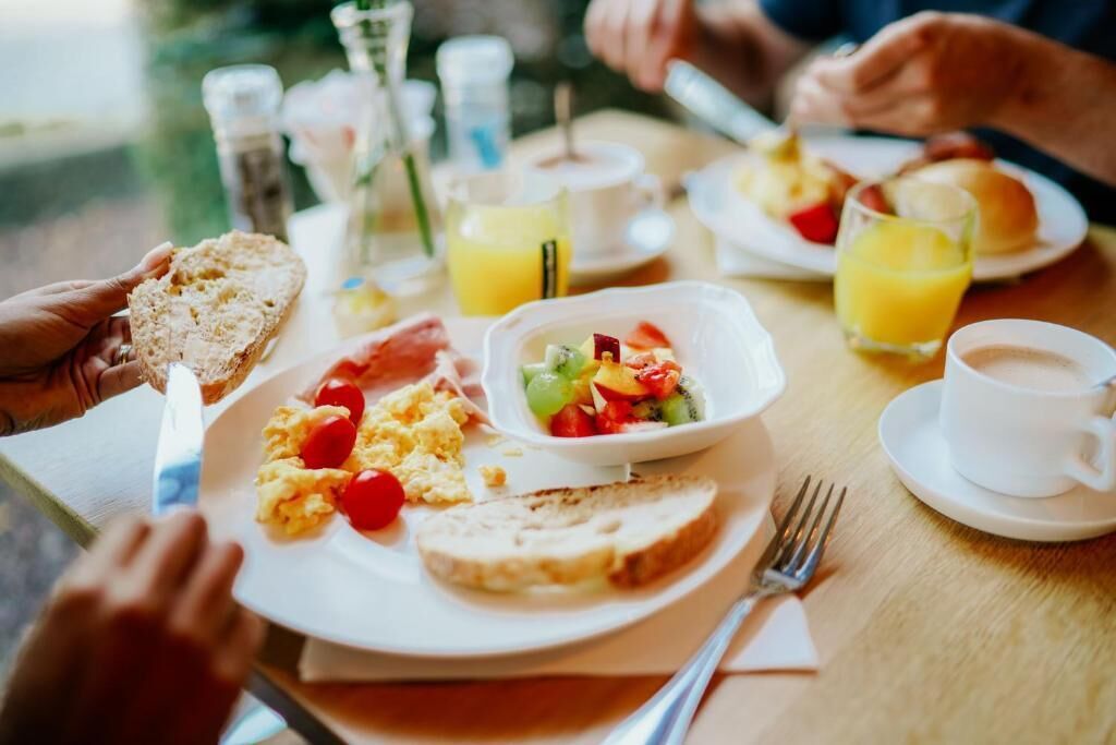 A breakfast setting with plates of scrambled eggs, toast, and fruit salad.