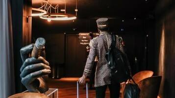 A person with a suitcase walking through a lobby with a modern design, including a unique sculpture and a stylish chandelier.