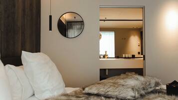A modern bedroom with a large bed, a round mirror, and a built-in wardrobe.