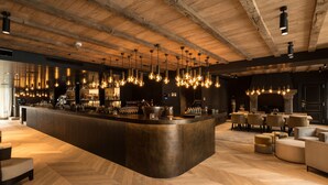 Un área de bar con mostrador curvo, lámparas colgantes y disposición de asientos.
