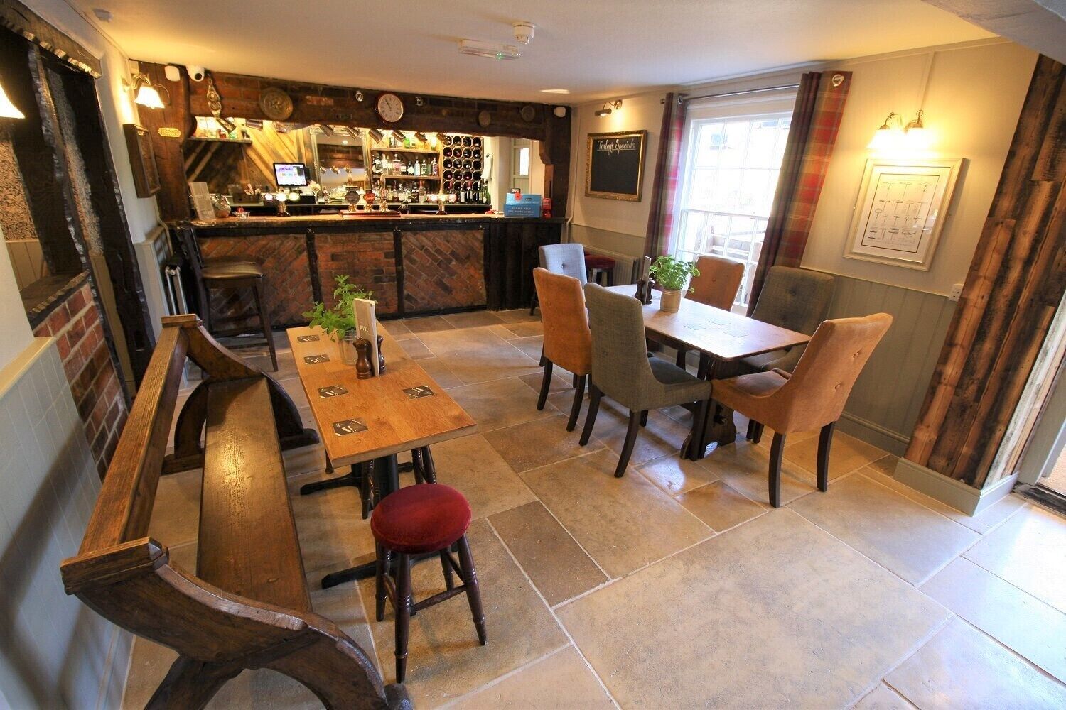 A cozy restaurant interior with a bar, wooden tables, and chairs.