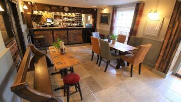 A cozy restaurant interior with a bar, wooden tables, and chairs.