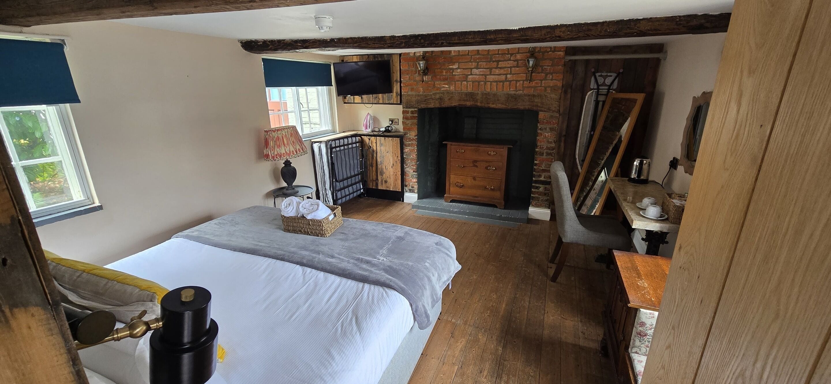 A bedroom with a bed, a dresser, a chair, a fireplace, and a window.