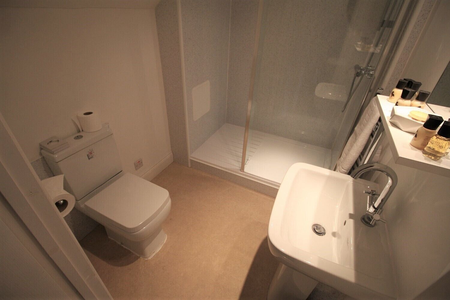 A bathroom with a toilet, a shower, and a sink.