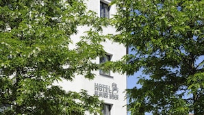 Un hotel con terraza al aire libre, fachada blanca y un letrero que dice 'HOTEL REINERBOUR'.