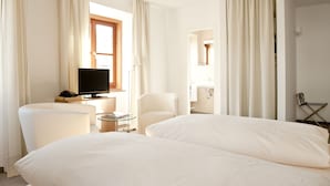 Habitación de hotel con dos camas, televisión, escritorio con lámpara y una silla.