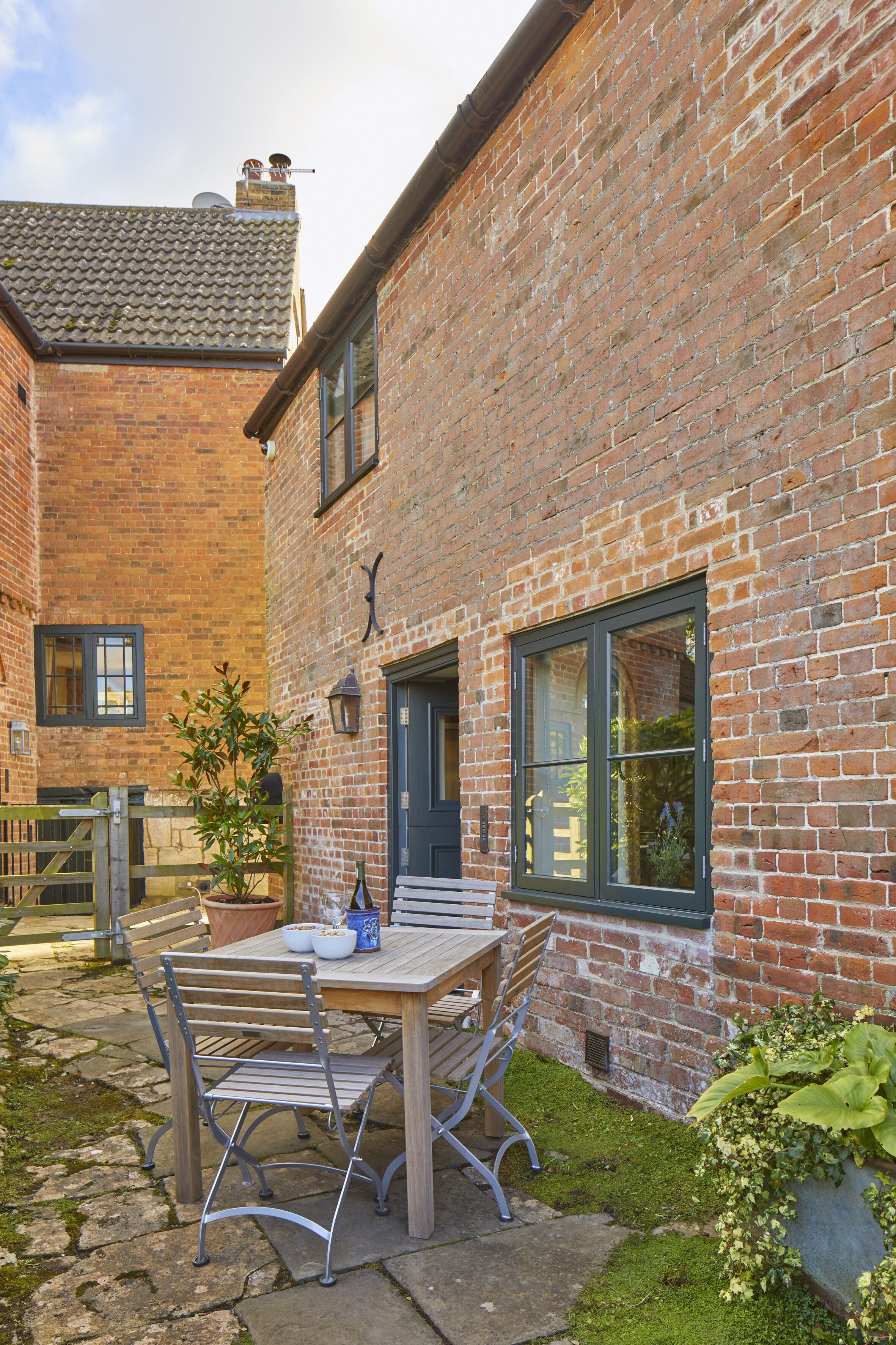 A brick building with a wooden table and chairs outside.