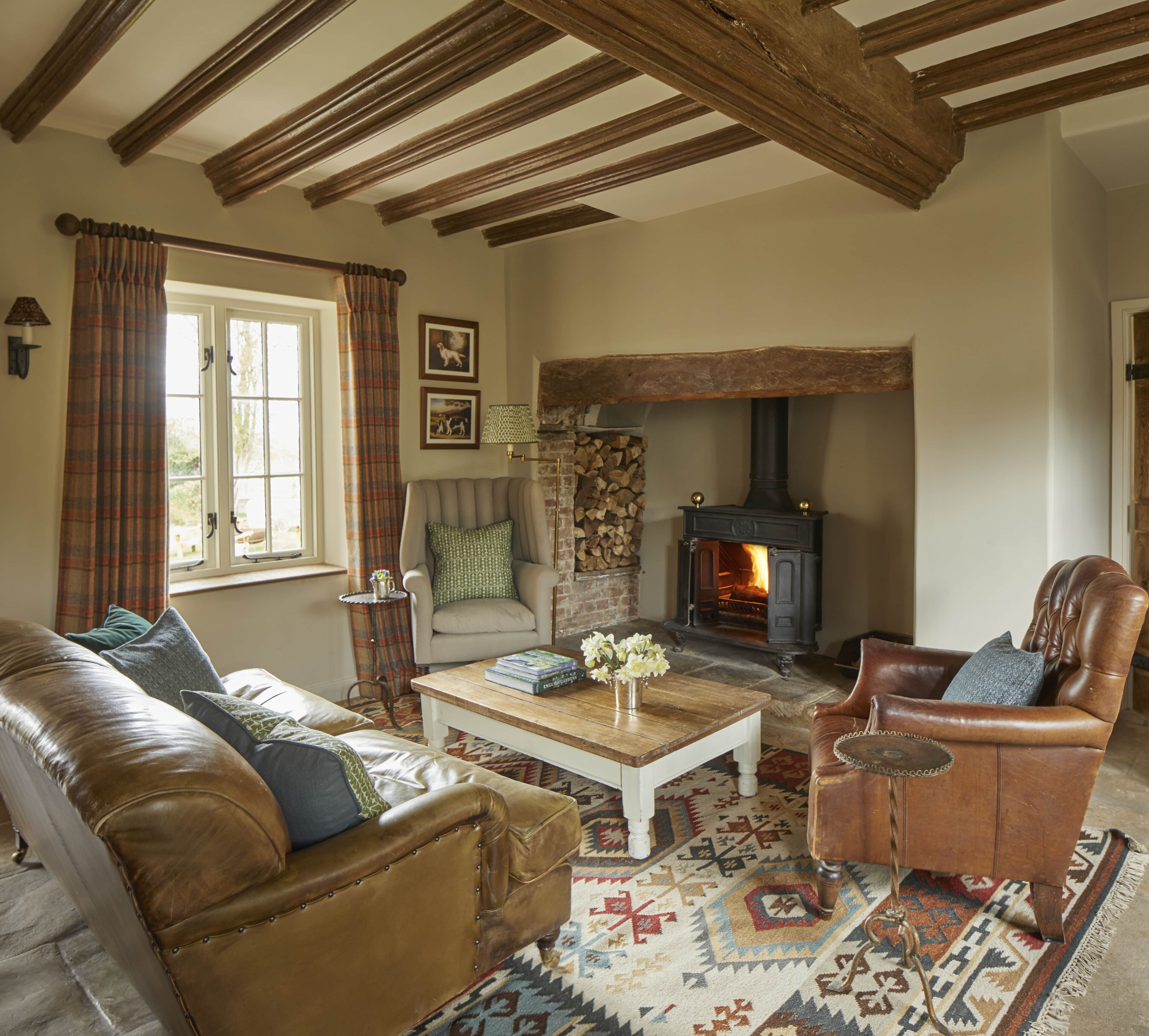 A cozy living room with a fireplace, leather furniture, and a patterned rug.