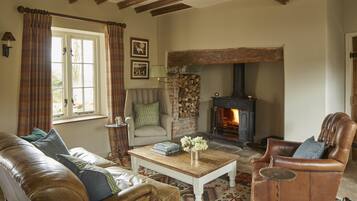 A cozy living room with a fireplace, leather furniture, and a patterned rug.