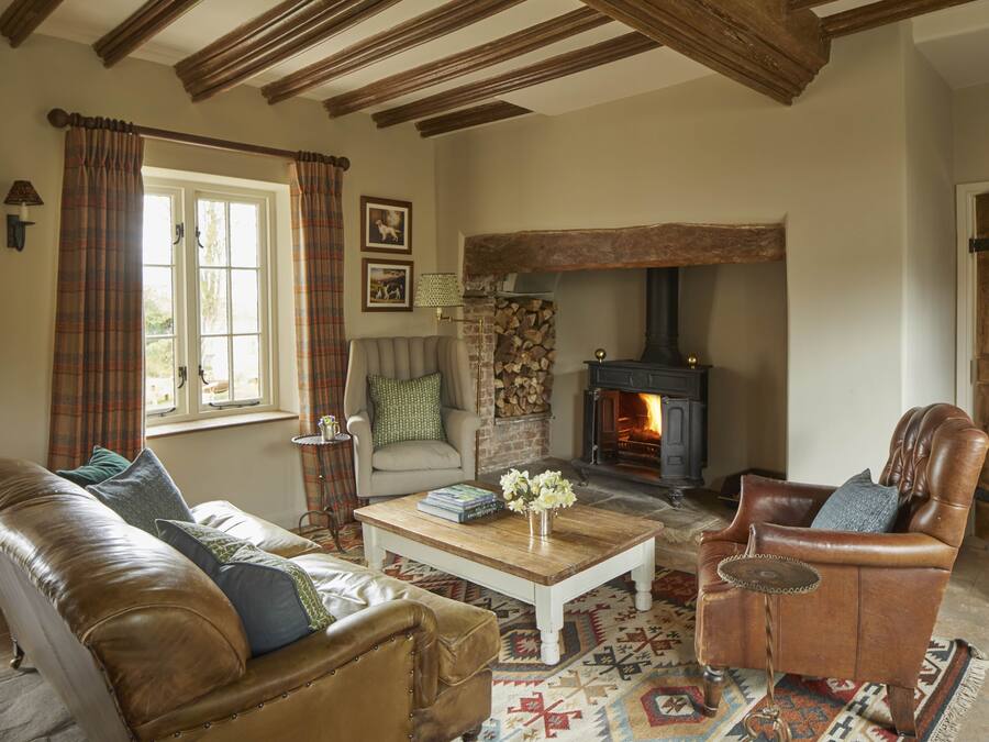 A cozy living room with a fireplace, leather furniture, and a patterned rug.