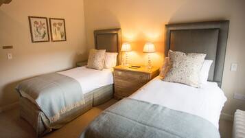 Una habitación de hotel con dos camas individuales, una mesita de noche con lámparas y un pequeño aparador.
