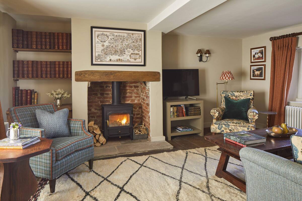 A cozy living room with a fireplace, bookshelves, a television, and comfortable seating.