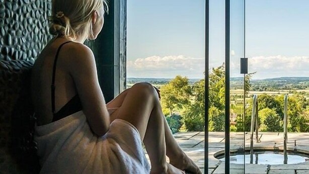 A person sitting by a window overlooking a landscape with trees and a body of water. - The Three Daggers (Westbury)