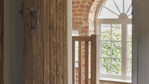 A room with a wooden door, a window with a brick wall, and a view of greenery outside. - The Three Daggers (Westbury)