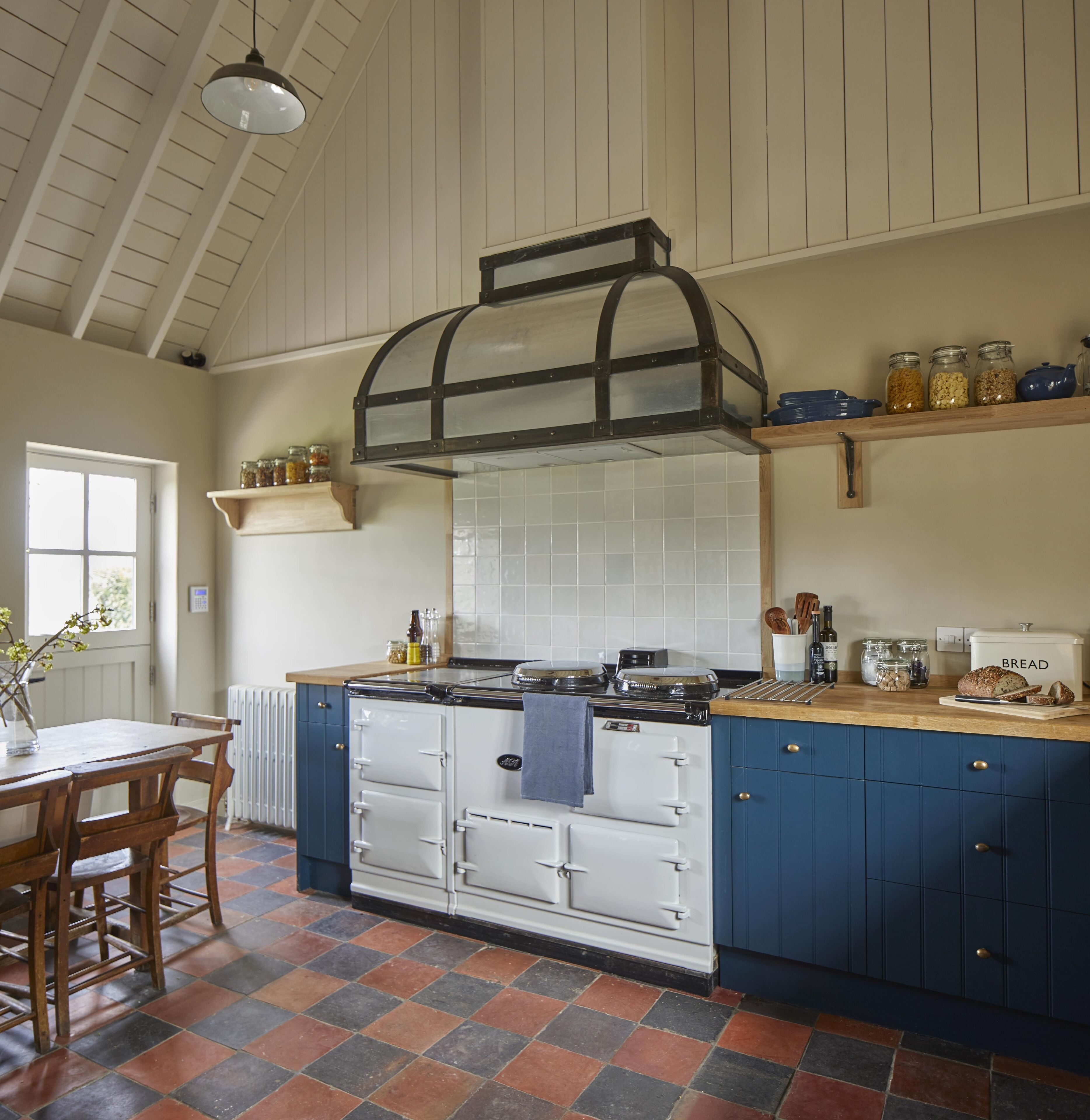 A kitchen with a built-in stove, a hanging light fixture, and a window.