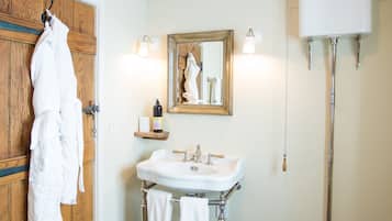 Ein Badezimmer mit Holztür, weißem Waschbecken mit Spiegel, Toilette und einer Badmatte aus Holz.