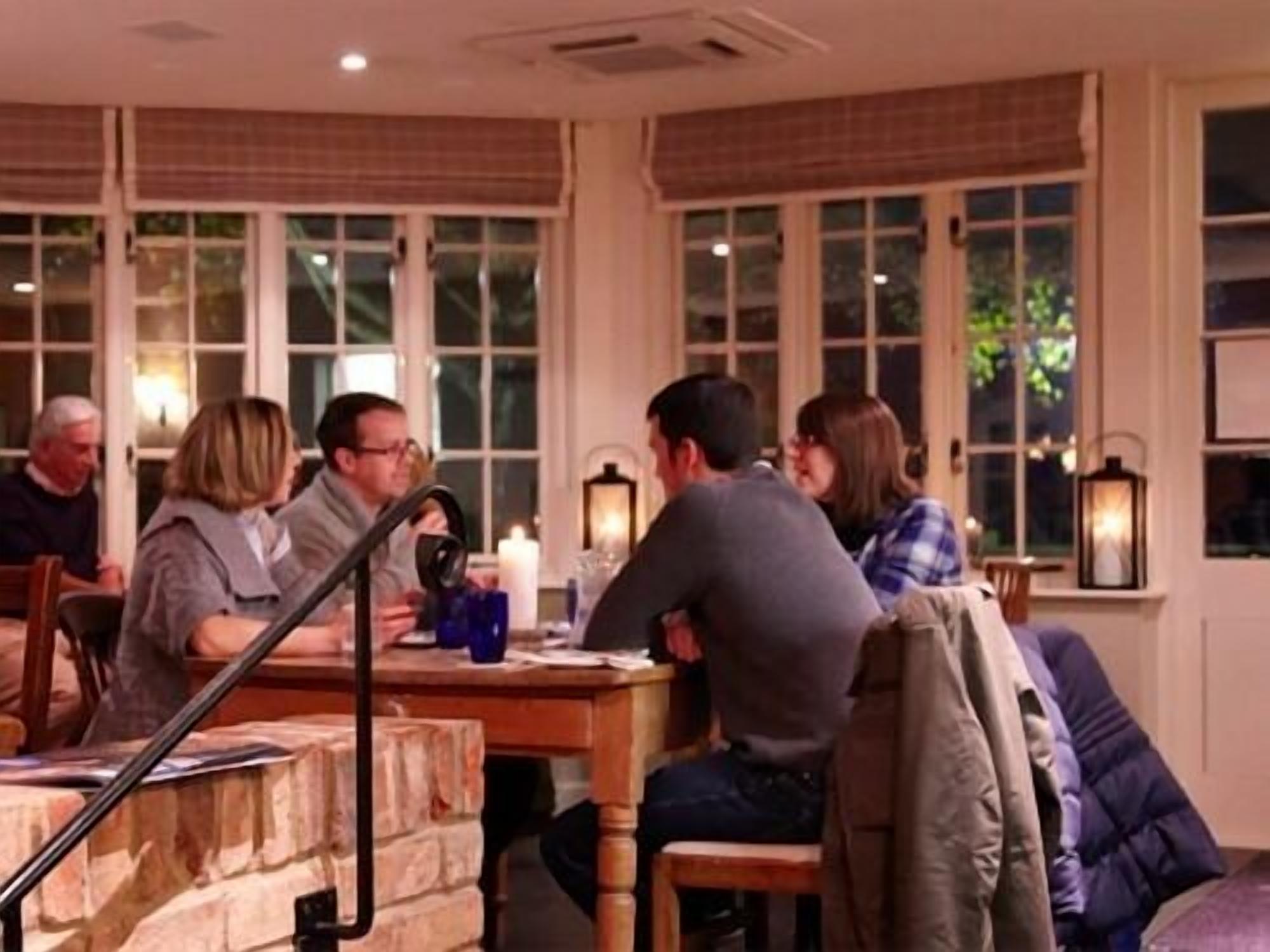 A cozy restaurant with a brick wall, large windows, and a wooden table.