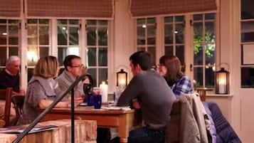 A cozy restaurant with a brick wall, large windows, and a wooden table.