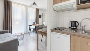 Une cuisine moderne équipée d’un lave-vaisselle, d’une machine à café et d’un four à micro-ondes. Un coin repas avec une table et des chaises est également à disposition.
