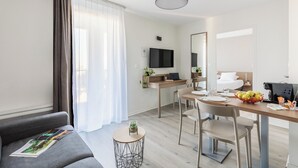 Une chambre d’hôtel moderne équipée d’un canapé, d’une table à manger et d’un téléviseur.