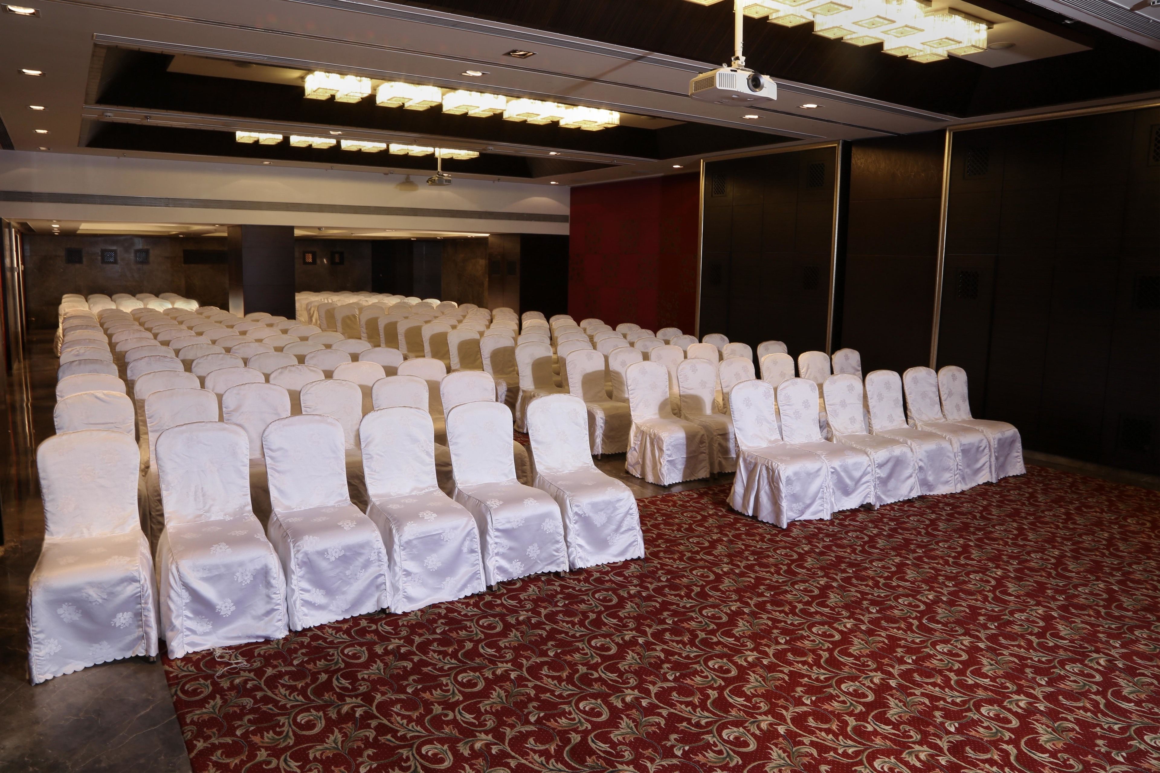 A conference room with rows of white chairs and a red carpet.