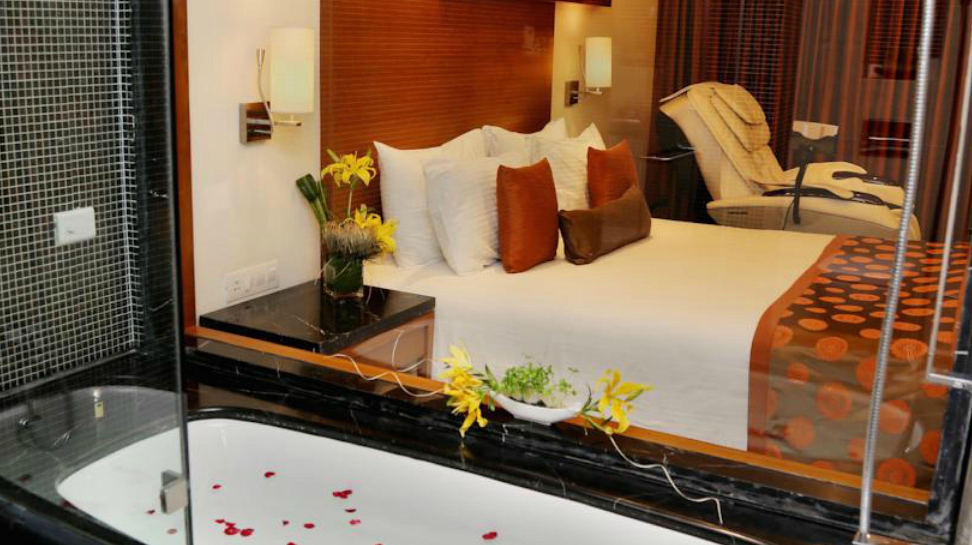 A hotel room with a bed, a bathroom with a bathtub, and a mirror reflecting the room.