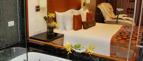 A hotel room with a bed, a bathroom with a bathtub, and a mirror reflecting the room.
