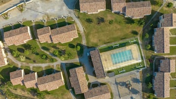 Vista aérea de una zona residencial con varias casas, una piscina central y áreas verdes circundantes.