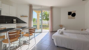 A modern hotel room with a kitchen area, a dining table with chairs, and two beds. - Résidence du Parc - Gorges de l'Hérault - Cévennes - Parc Sports & Loisirs Brissac Ganges (Brissac)