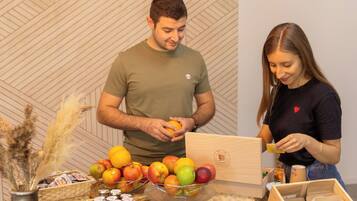 Een man en een vrouw staan bij een tafel vol fruit en potten.